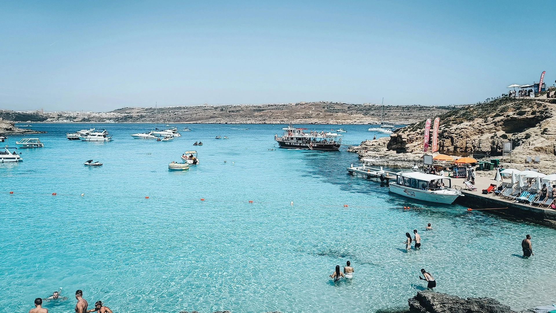 Boats anchored in the bright turquoise water of the Blue Lagoon in Comino