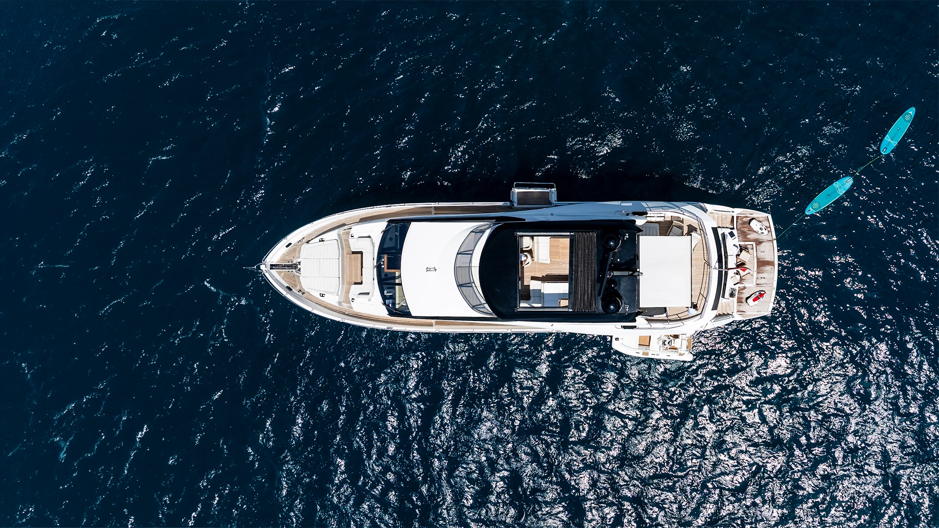 Aerial view of the Sunseeker 86 JUPJU under way with paddleboards astern